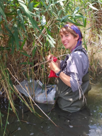 [Translate to English:] Porträt von Katharina Mahr beim Probensammeln im Wasser