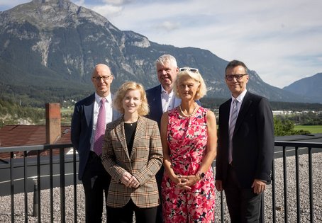 2 elegant gekleidete Frauen und 3 M&auml;nner vor einer Bergkulisse