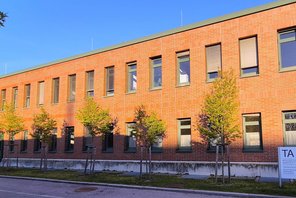 Backsteingeb&auml;ude mit kleinen B&auml;umen davor