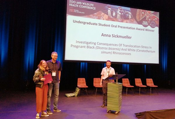 Female student and two males at an award ceremony