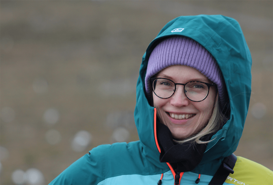 Isabella Mayer mit Kapuze und Regenjacke in der Natur. 