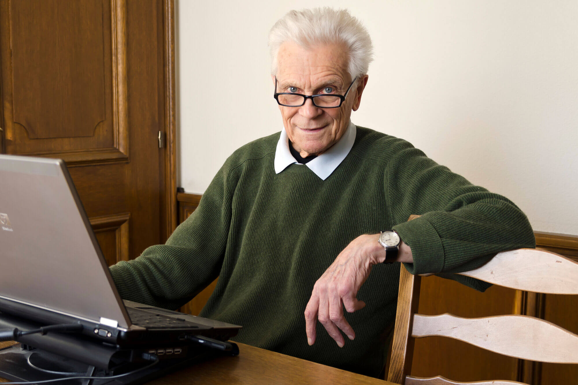 Portr&auml;t von Ernst Brandl, am Schreibtisch sitzend mit aufgeklapptem Laptop vor sich.